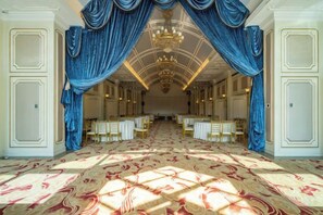 A grand hall with a patterned carpet, rows of tables, and blue drapes. - Reignwood Pine Valley (Beijing)
