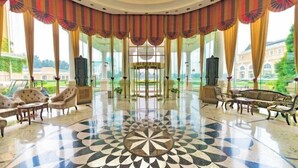 A spacious lobby with a patterned floor, elegant furniture, and large windows offering a view of a garden and buildings. - Reignwood Pine Valley (Beijing)