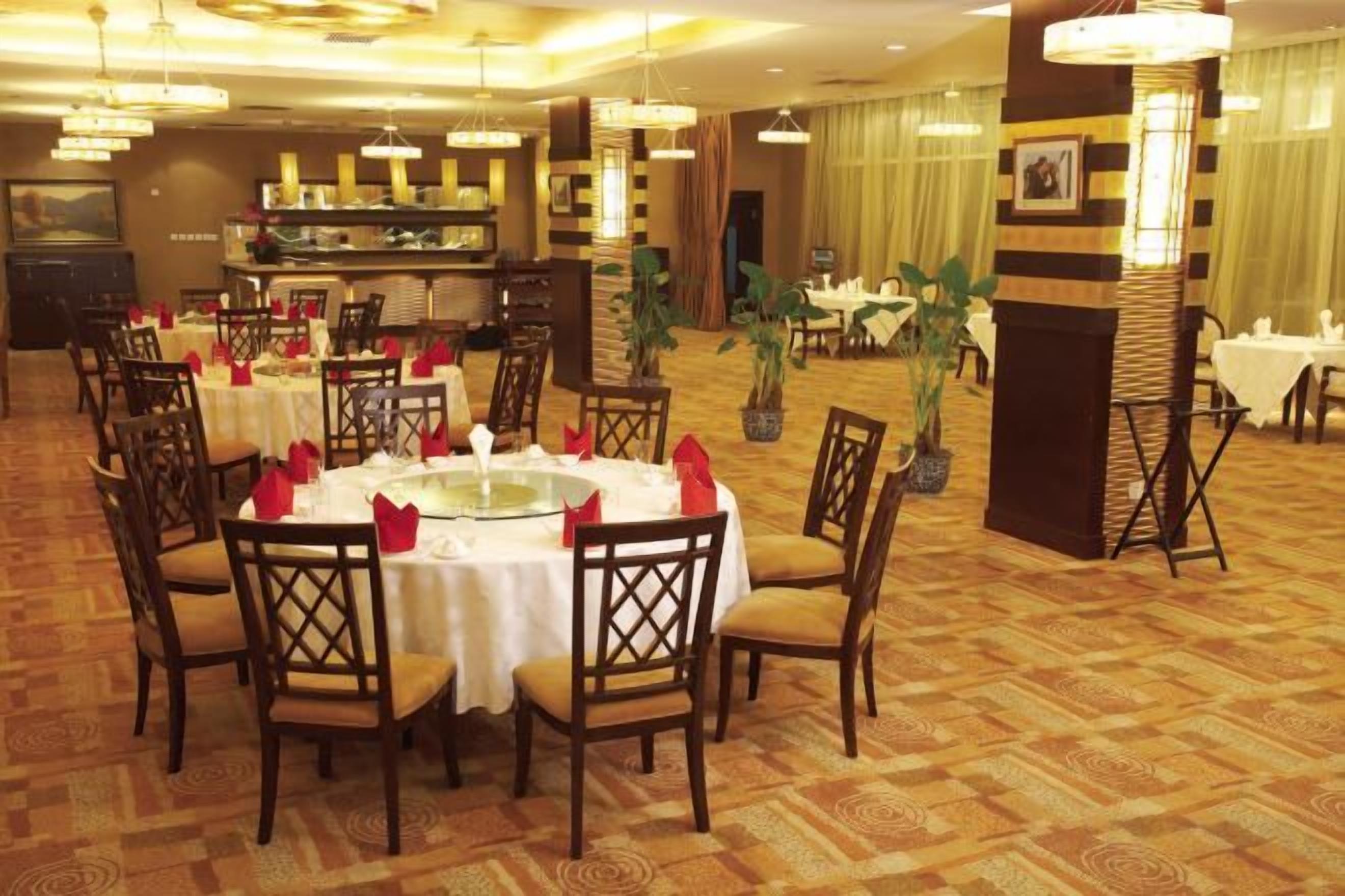 Een eetruimte met ronde tafels, stoelen en een buffet.