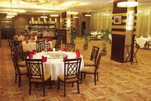 Ein Essbereich mit runden Tischen, Stühlen und einem Buffet.