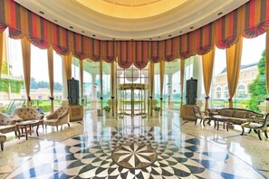 A grand lobby with a central chandelier, elegant seating, and a large window offering a view of the outdoors. - Reignwood Pine Valley (Beijing)