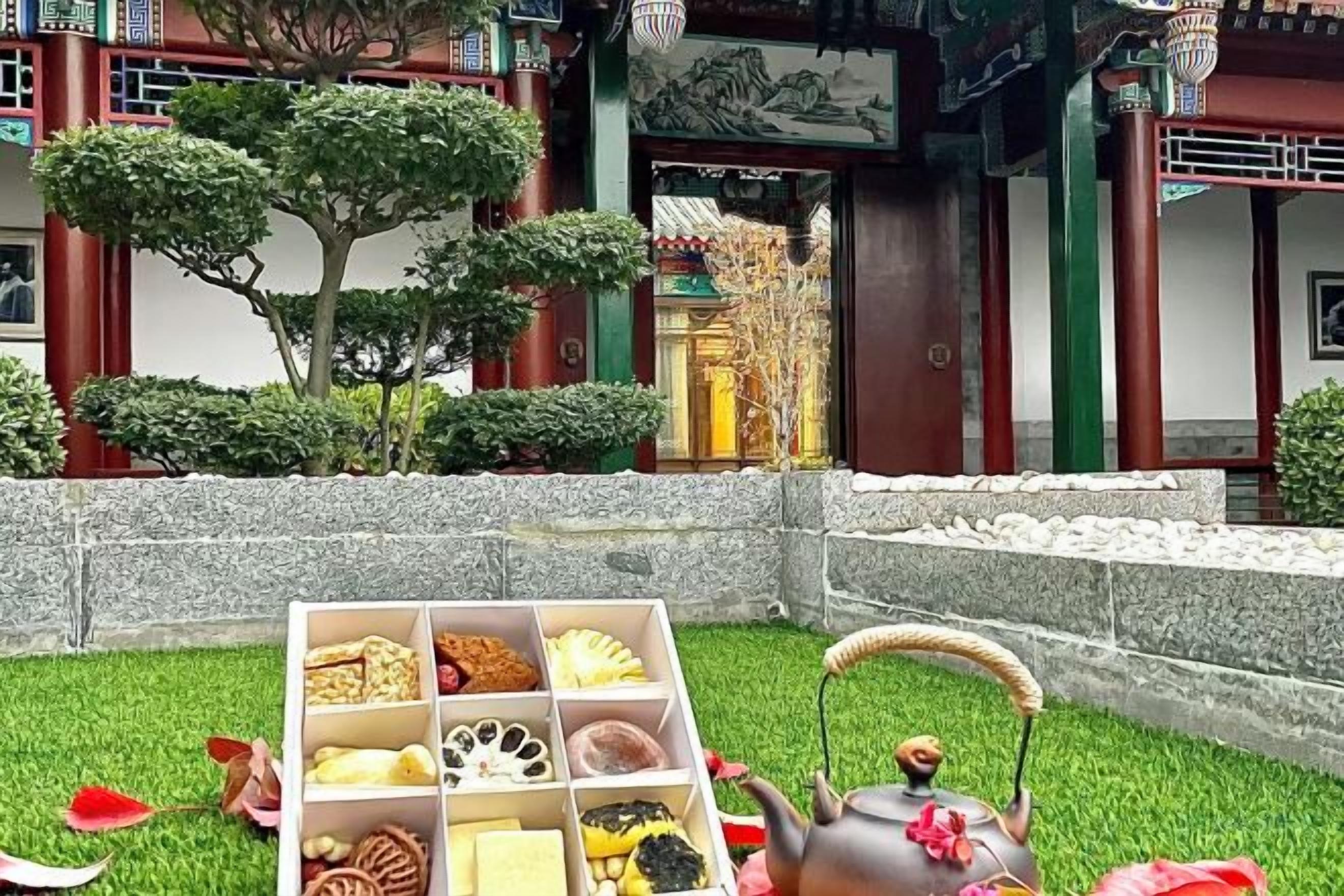 A traditional building with a courtyard, a stone wall, and a tea set on the grass.