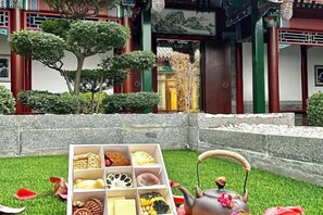 A traditional building with a courtyard, a stone wall, and a tea set on the grass. - Reignwood Pine Valley (Beijing)