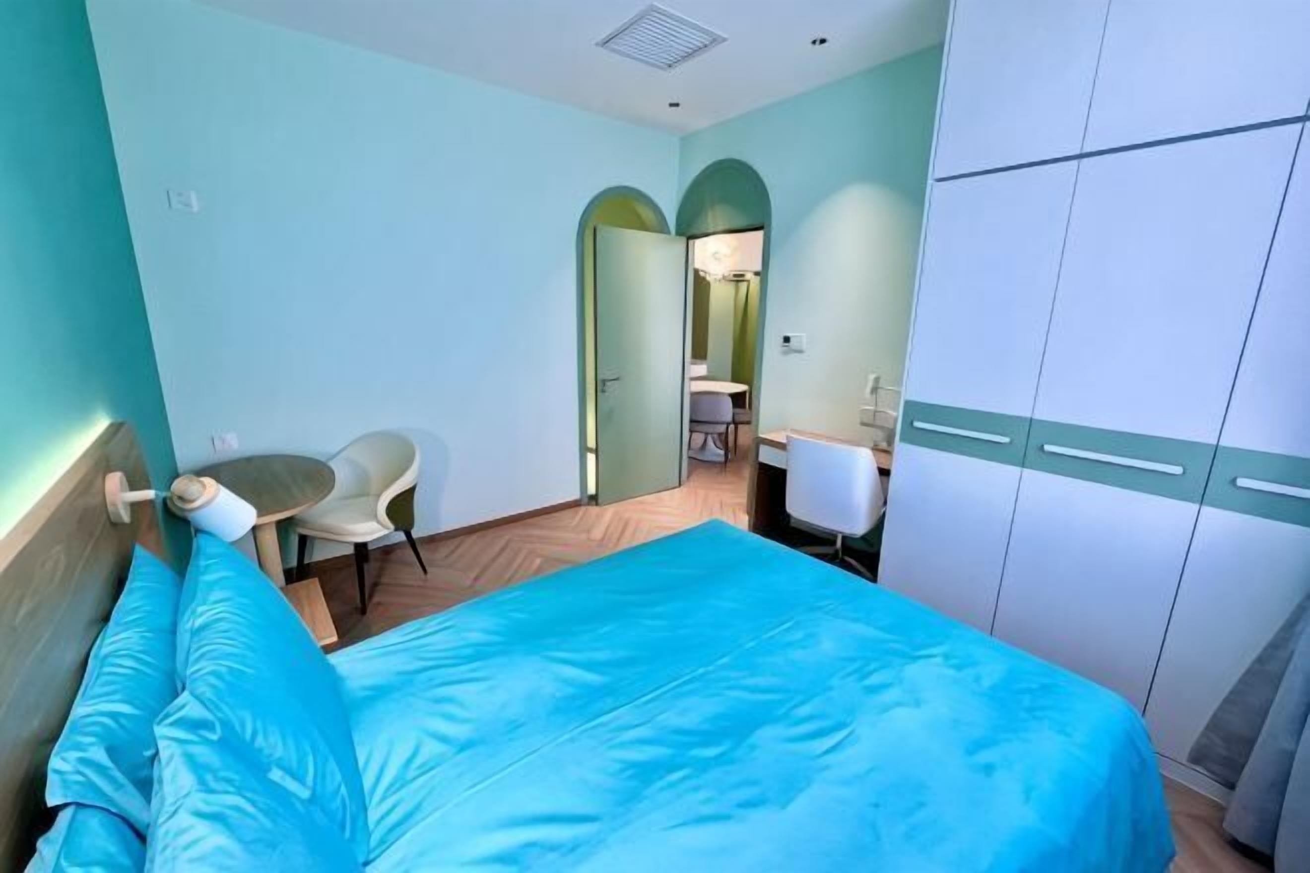 Een slaapkamer met een bed, een bureau, een stoel en een kledingkast.