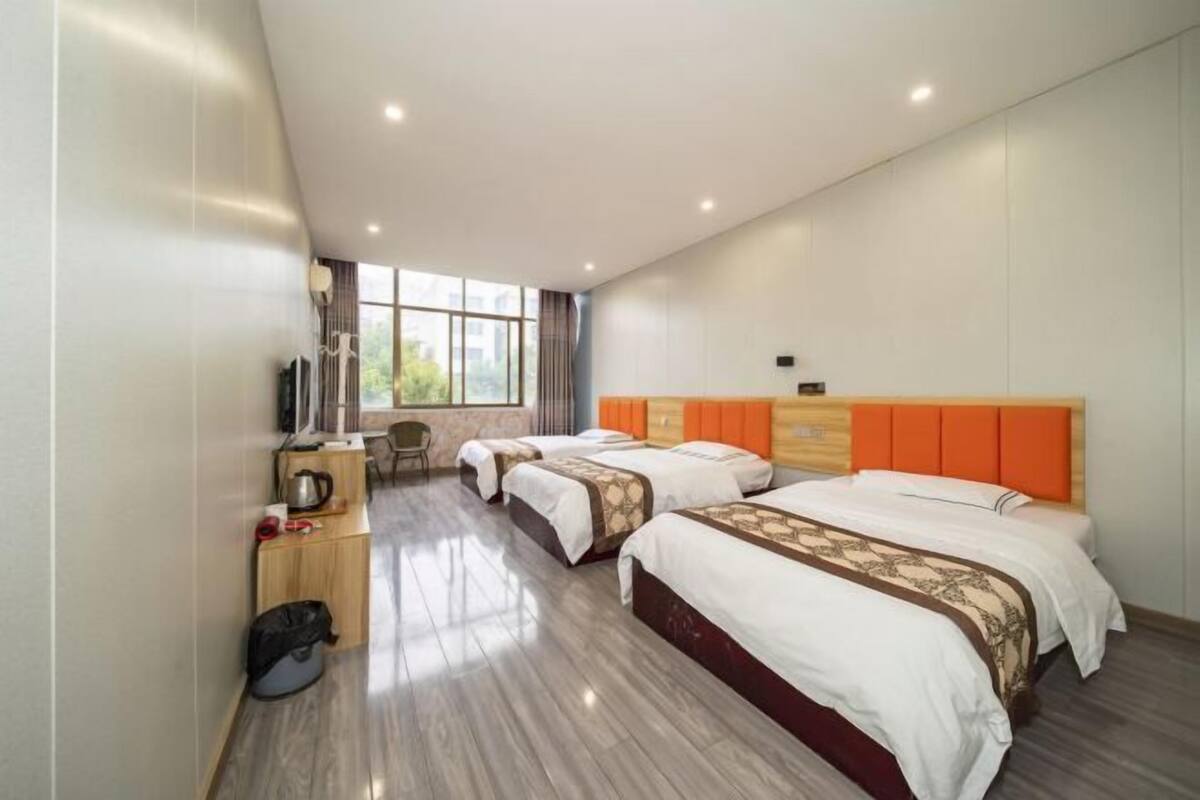 Une chambre d’hôtel avec deux lits, un bureau, une chaise et une fenêtre.
