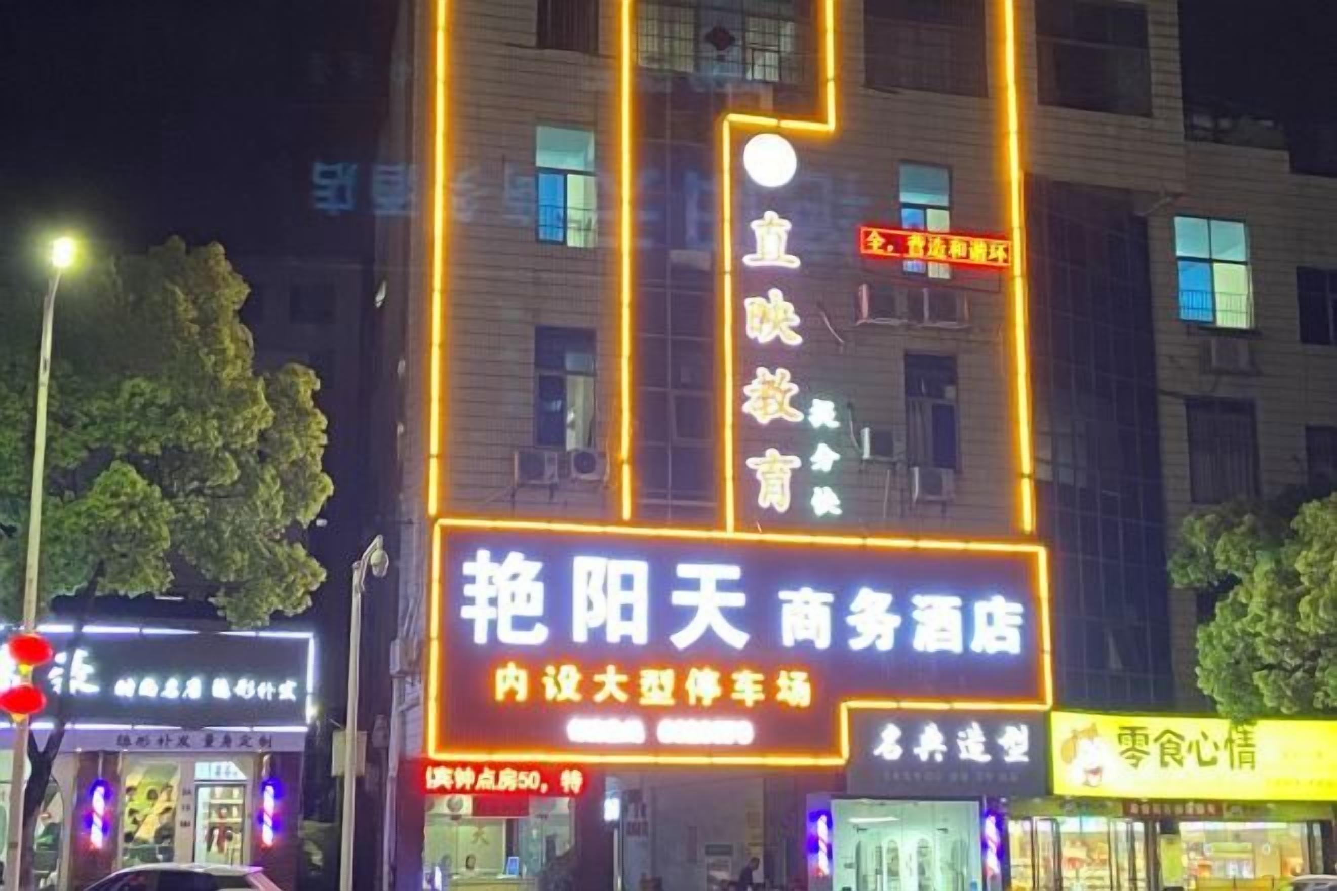 A building with illuminated signage, including a prominent sign for a business hotel and a smaller sign for a restaurant.