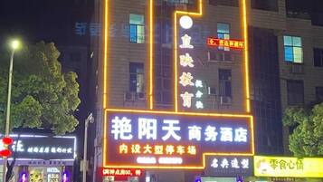 A building with illuminated signage, including a prominent sign for a business hotel and a smaller sign for a restaurant.