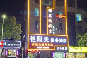 Un edificio con señalización iluminada, incluyendo un letrero llamativo para un hotel de negocios y un letrero más pequeño para un restaurante.