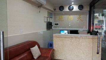 A reception area with a reception desk, a brown leather sofa, and a wall-mounted clock.