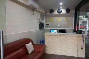Un área de recepción con mostrador, un sofá de cuero marrón y un reloj en la pared.