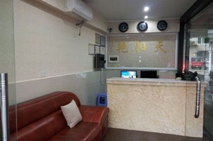 Un área de recepción con mostrador, un sofá de cuero marrón y un reloj en la pared.