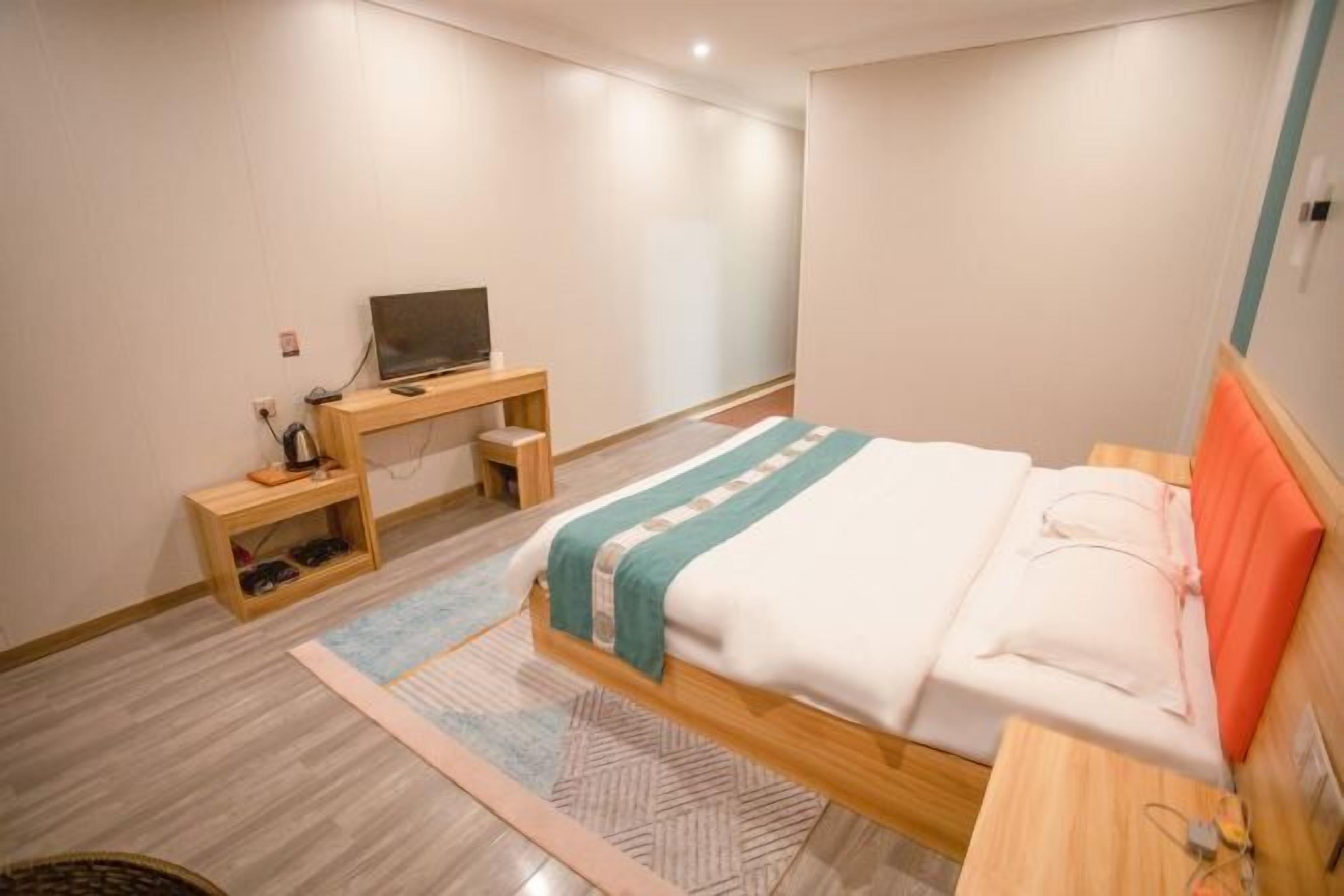 A bedroom with a bed, a desk, and a television.
