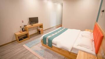 A bedroom with a bed, a desk, and a television.
