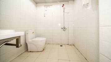 A small, white bathroom with a toilet, a shower, and a sink.