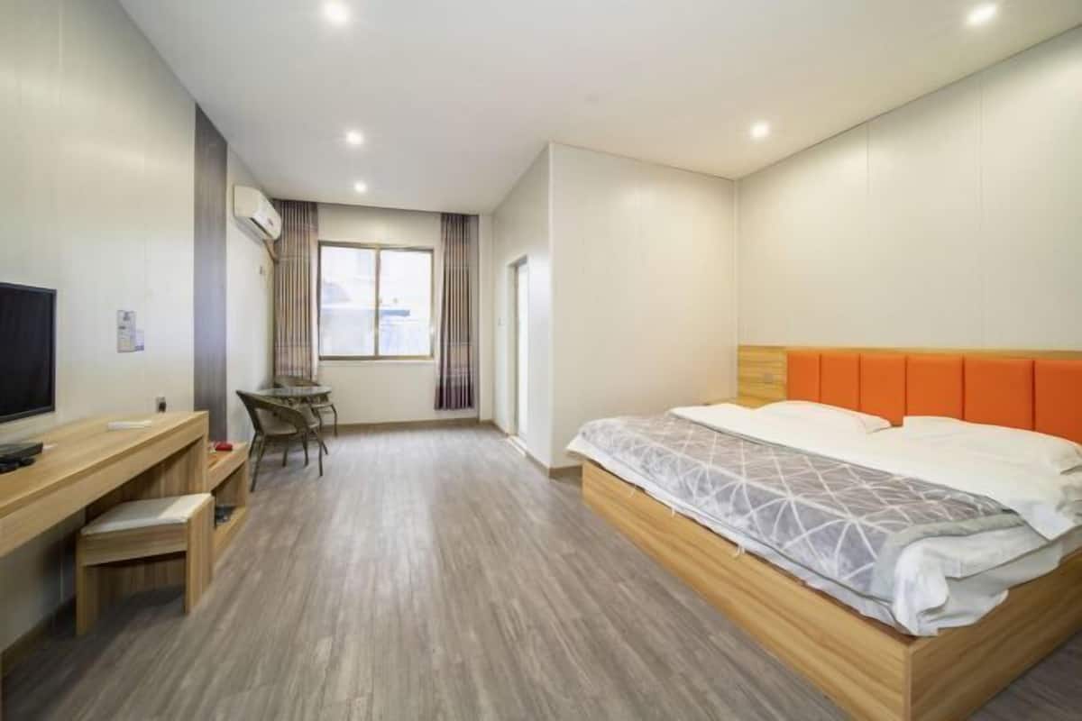 Une chambre d’hôtel avec un lit, un bureau, une chaise, une télévision et une fenêtre.
