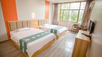 A hotel room with two beds, a desk, a chair, and a large window with curtains.