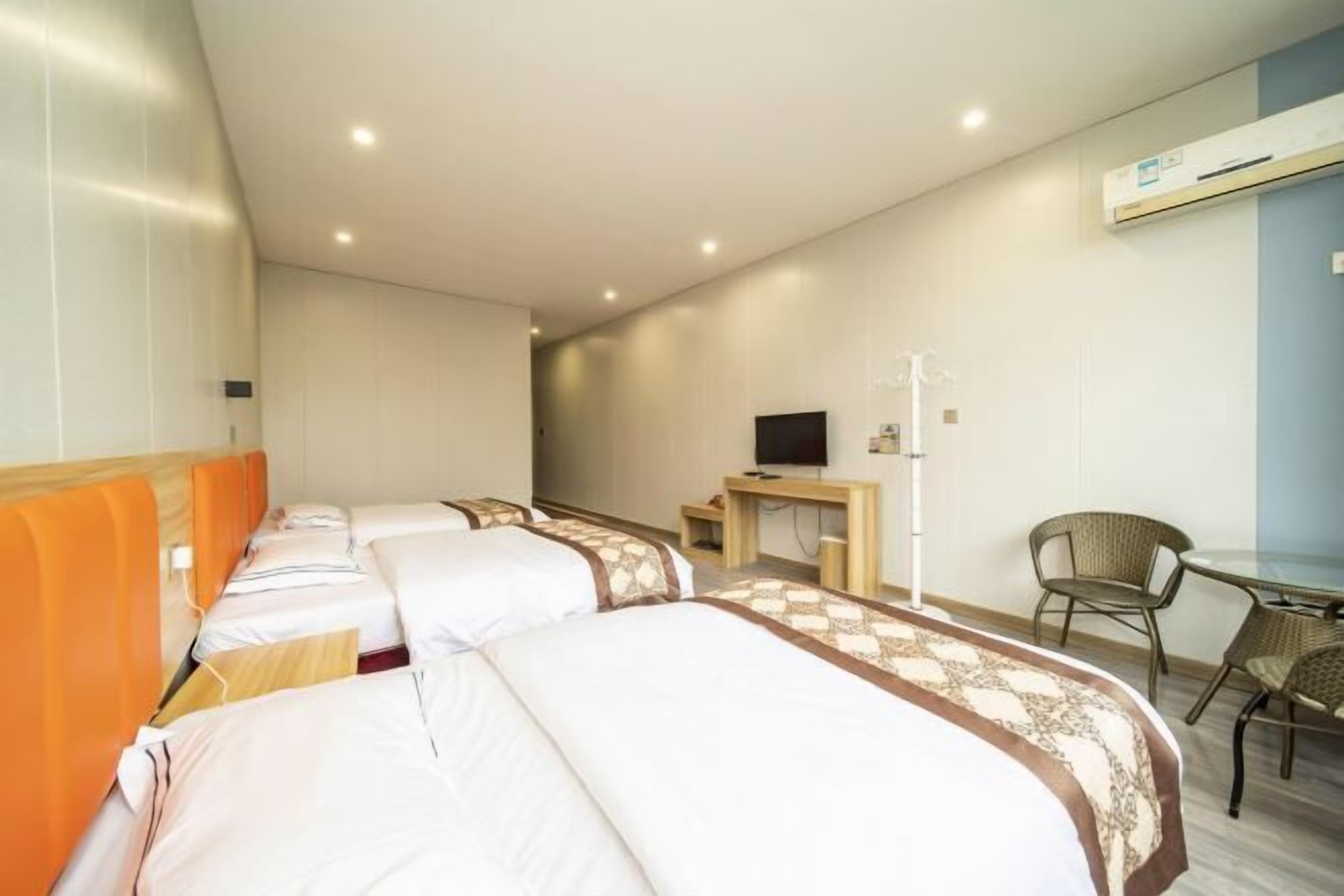 Habitación de hotel con tres camas, un escritorio, un televisor y una silla.