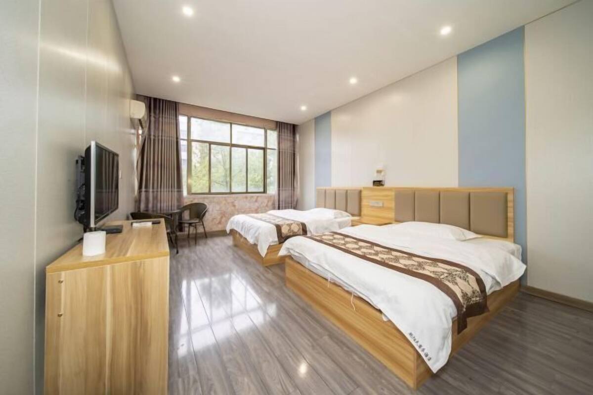 Une chambre d’hôtel avec un lit, un bureau, une chaise, une télévision et une fenêtre.
