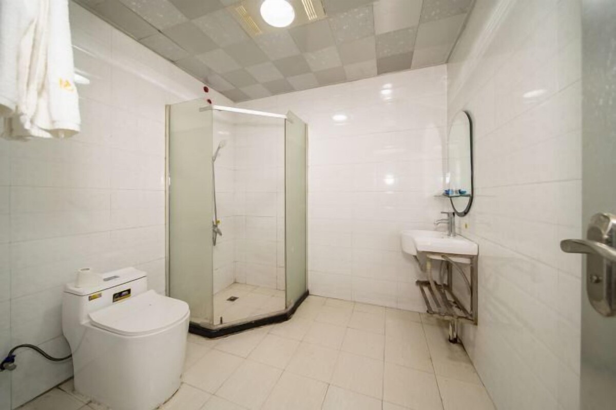 A bathroom with a toilet, a glass-enclosed shower, and a sink with a mirror.