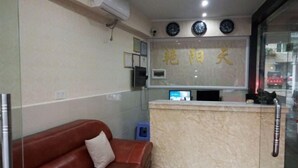 A reception area with a marble counter, a brown leather sofa, and a wall with clocks and framed pictures. - Yanyangtian Business Hotel (Yongzhou)