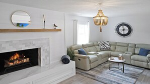 Una sala de estar con chimenea, un espejo redondo, un reloj y una araña.