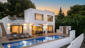 Uma casa moderna de dois andares, com piscina, área de estar externa e um pátio bem iluminado.