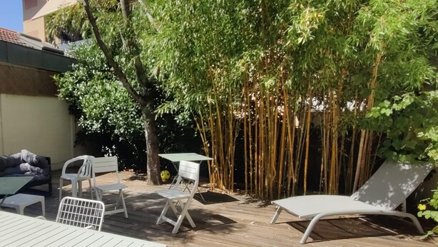 An outdoor patio with a wooden deck, white furniture, and a bamboo fence. - House with garden near the beach of Arcachon (Arcachon)