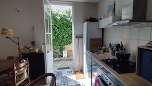 A kitchen with a dining area, a stove, a sink, and a television. - House with garden near the beach of Arcachon (Arcachon)