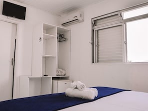 A bedroom with a bed, a wardrobe, a desk, an air conditioner, and a window with blinds. - Hanna Amsterdam Hotel & Eventos (Florianópolis)