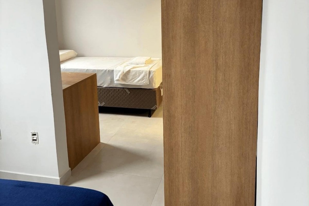 A bedroom with a bed, a wooden nightstand, and a blue bedspread.