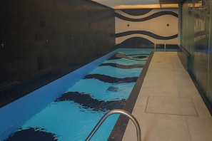 An indoor swimming pool with a tiled wall featuring a wave pattern. - Hanna Amsterdam Hotel & Eventos (Florianópolis)