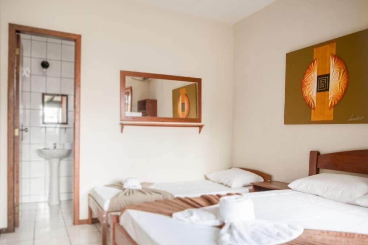 A hotel room with two beds, a bathroom, and a large mirror.