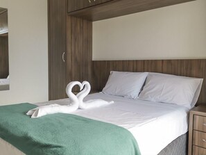 A hotel room with a bed, a green throw blanket, and a swan-shaped towel on the bed. - Hanna Amsterdam Hotel & Eventos (Florianópolis)