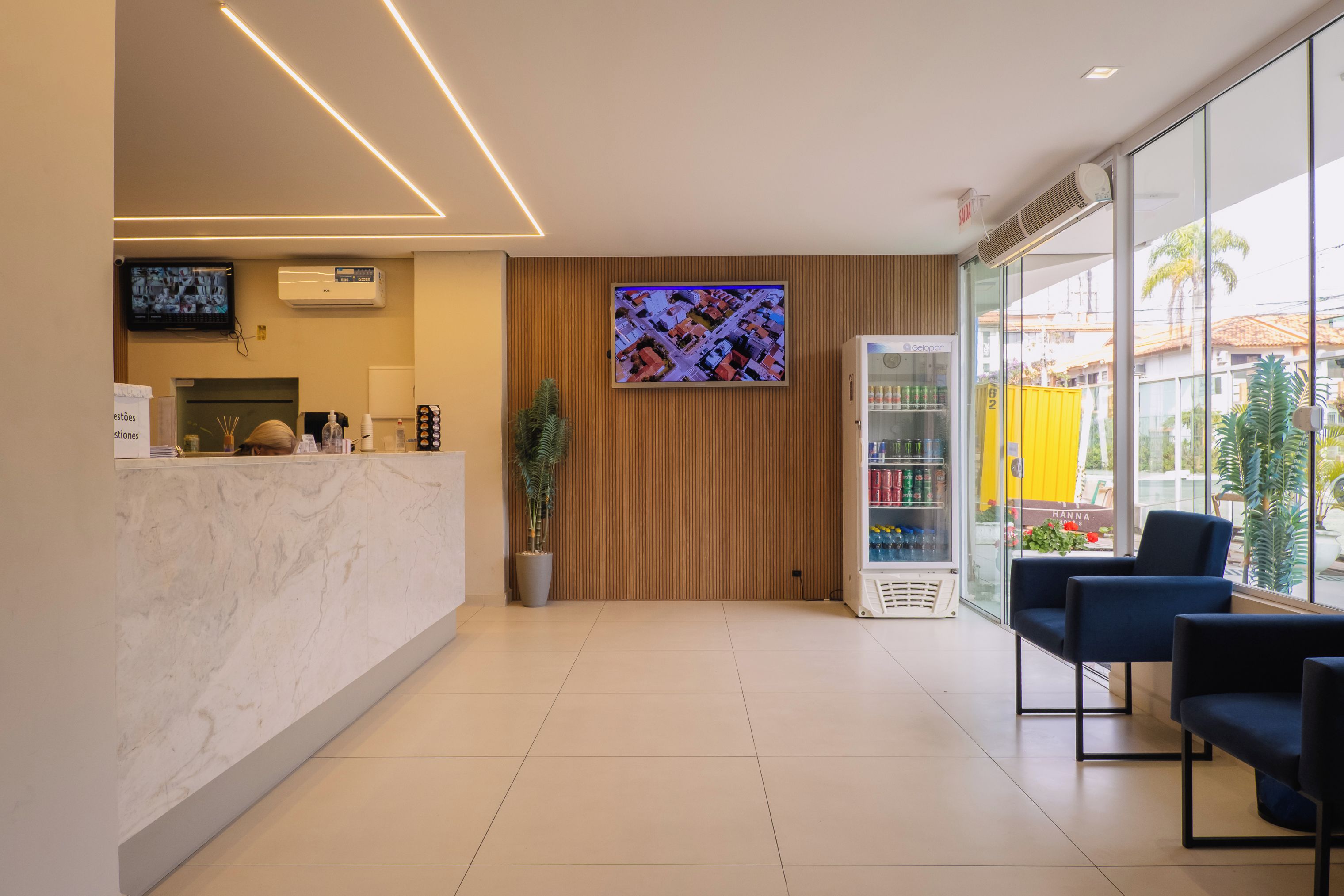 Una moderna recepción con mostrador de mármol, una pantalla de televisión grande y una zona de estar con sillas.