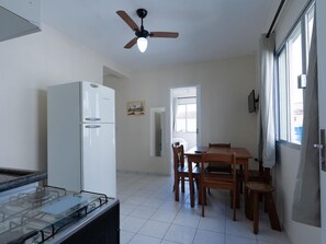 A kitchen with a white refrigerator, a gas stove, a ceiling fan, and a dining area with a wooden table and chairs. - Hanna Amsterdam Hotel & Eventos (Florianópolis)