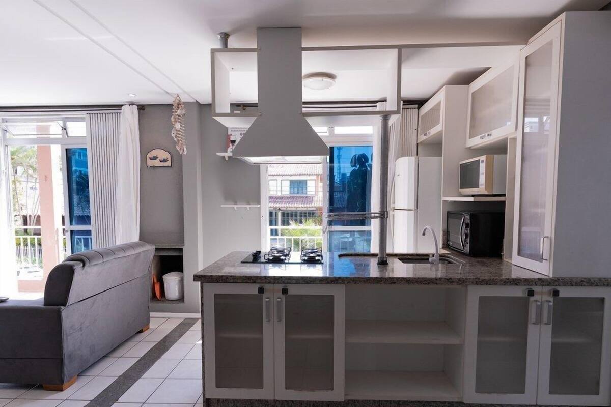 A modern kitchen with a central island, built-in cabinets, and a large window providing a view of the outdoors.