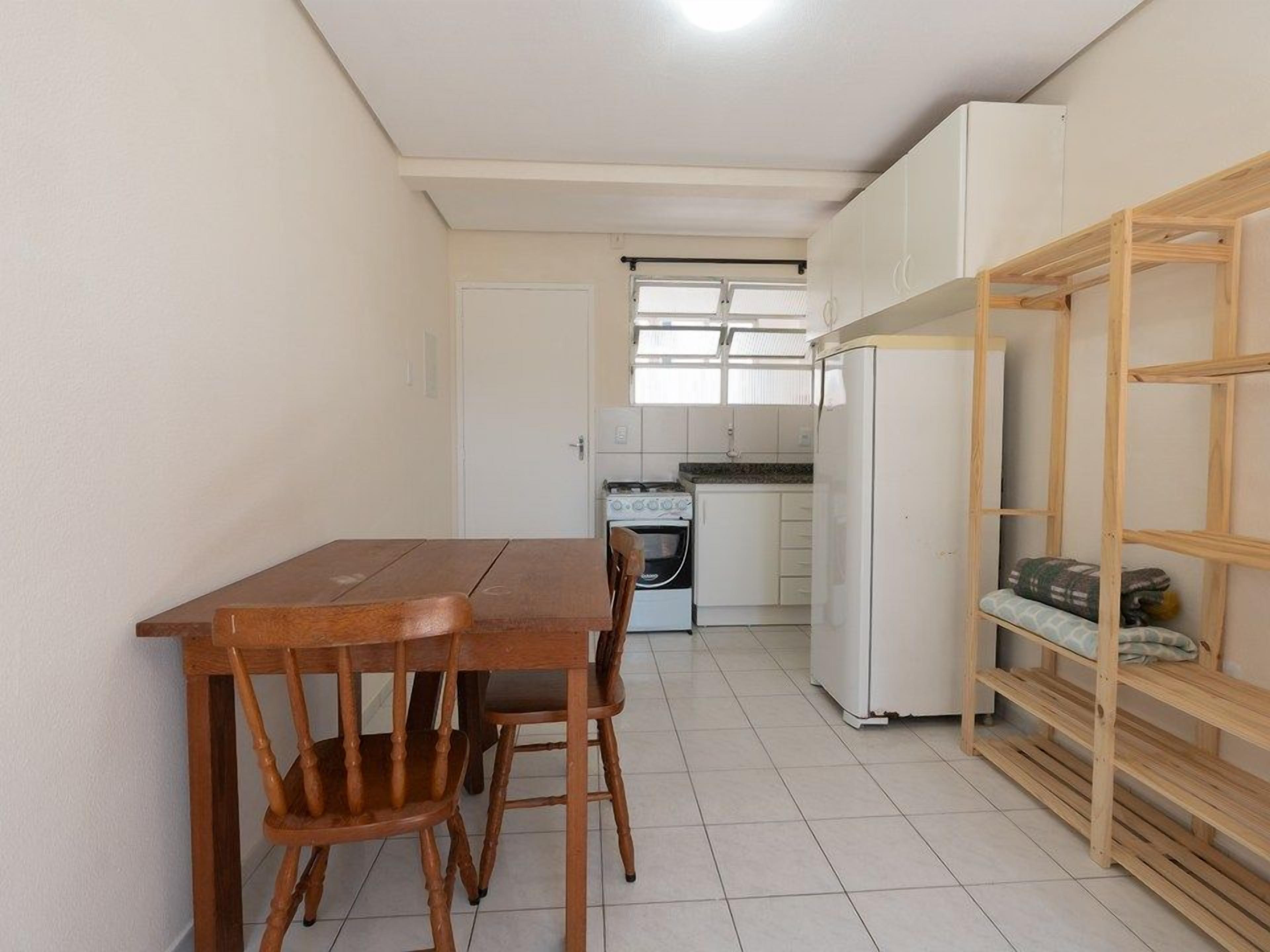 A compact kitchen with a dining table and chairs, a stove, and a refrigerator.