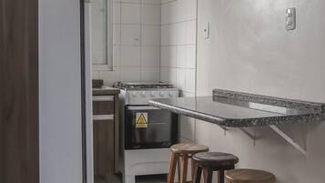 Una cocina con estufa a gas, horno y taburetes de madera.