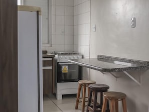 A kitchen with a gas stove, oven, and wooden stools. - Hanna Amsterdam Hotel & Eventos (Florianópolis)
