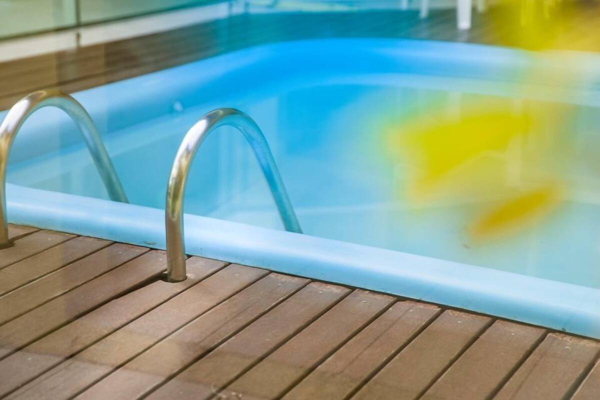 A swimming pool with clear water and a wooden deck.