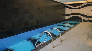 Una piscina con barandillas metálicas, paredes y suelo de baldosas.