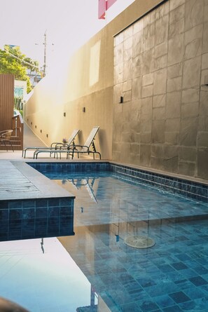 A swimming pool with tiled flooring and lounge chairs. - Hanna Amsterdam Hotel & Eventos (Florianópolis)