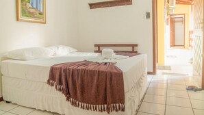 Een slaapkamer met een bed, een schilderij aan de muur en een houten plank.