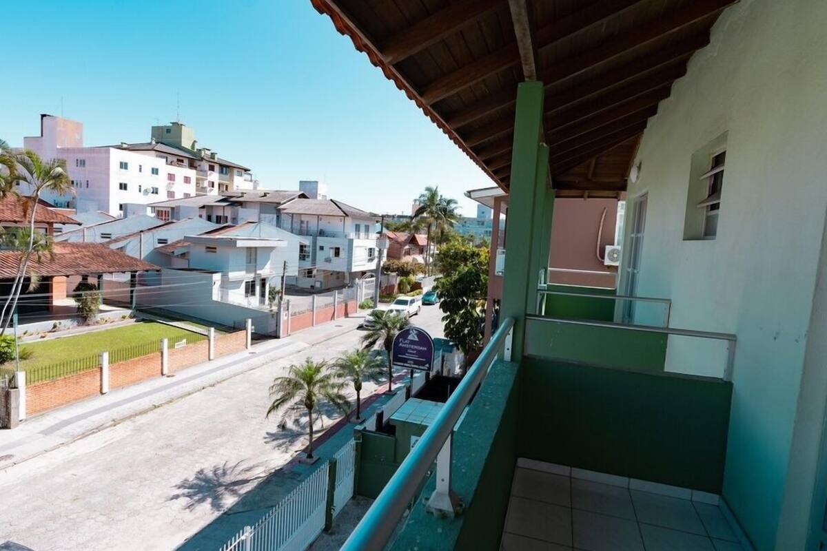 A balcony with a view of a residential area, including houses and a street.