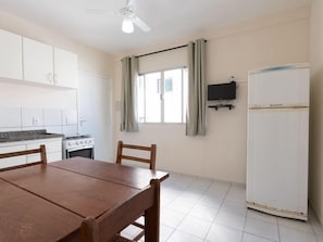A kitchen with white cabinets, a stove, and a dining table with chairs. - Hanna Amsterdam Hotel & Eventos (Florianópolis)