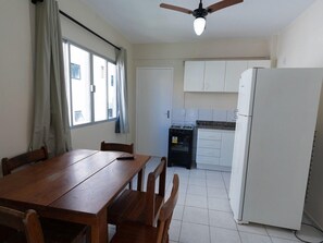 A compact kitchen with white cabinets, a refrigerator, and a gas stove. - Hanna Amsterdam Hotel & Eventos (Florianópolis)