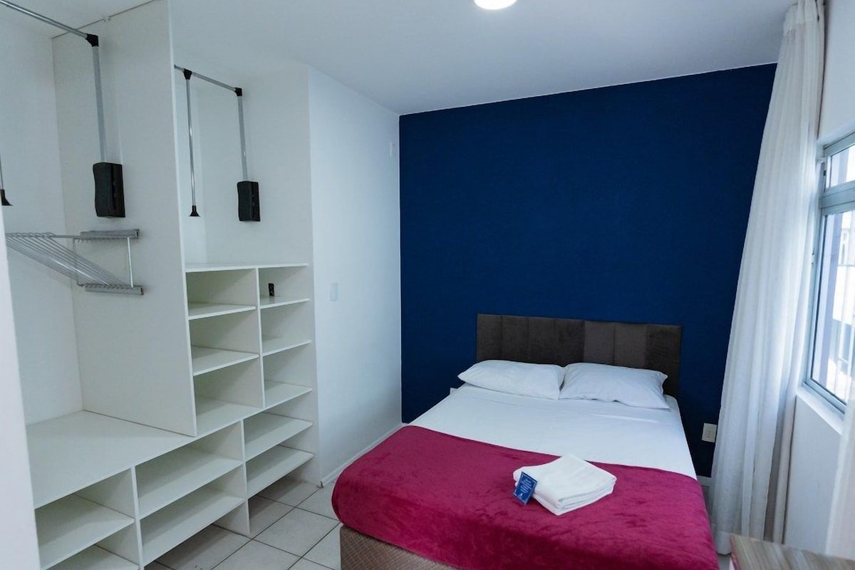 A hotel room with a bed, a wardrobe, and a window.