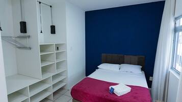 Una habitación de hotel con una cama, un armario y una ventana.