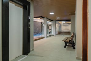 En gang med bænk, glasdøre og flisegulv.
