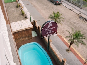 A sign for Flat Amsterdam, a swimming pool, and a street view with a parked car. - Hanna Amsterdam Hotel & Eventos (Florianópolis)